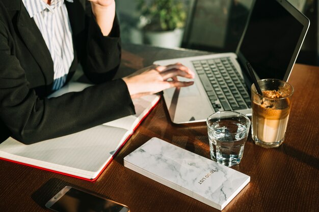 Close-up of a businesswoman's hand using laptop over wooden desk