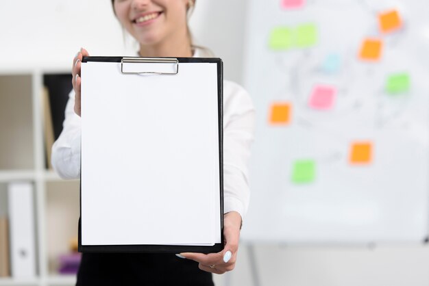 Close-up of businesswoman showing white paper on clipboard