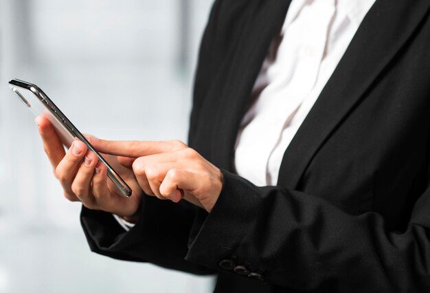 Close-up of a businesswoman touching smartphone with finger