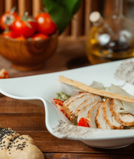 Foto gratuita primo piano di insalata caesar con fette di pollo alla griglia, parmigiano e grissino