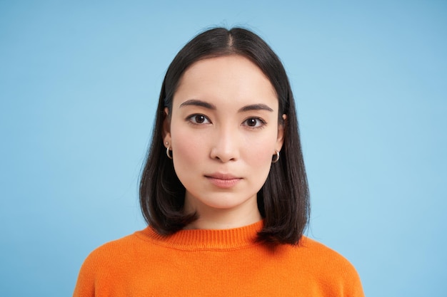 Close up of candid young asian woman looking at camera with genuine natural emotions standing over b