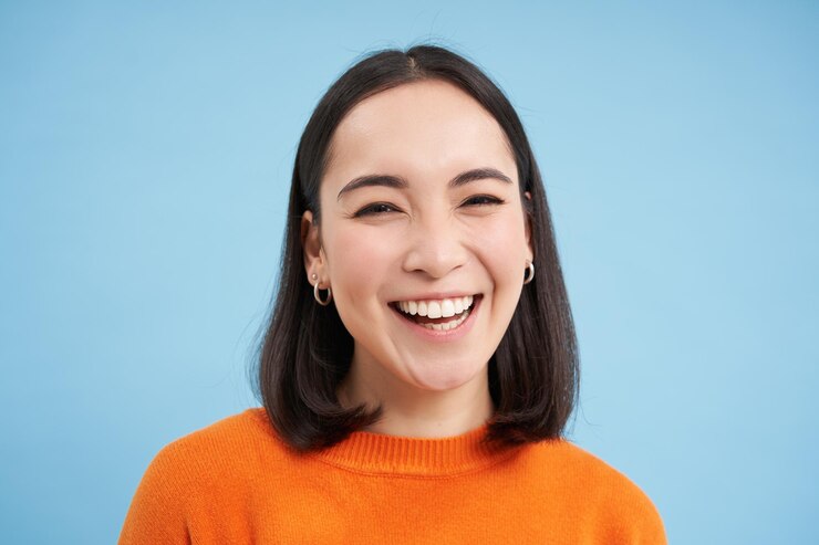 무료 Photo b 위에 서 있는 진정한 자연의 감정으로 카메라를 보고 있는 솔직한 젊은 아시아 여성의 클로즈업