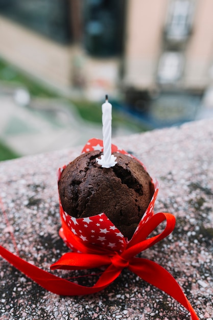 Close-up of candle on cake decorated with red ribbon