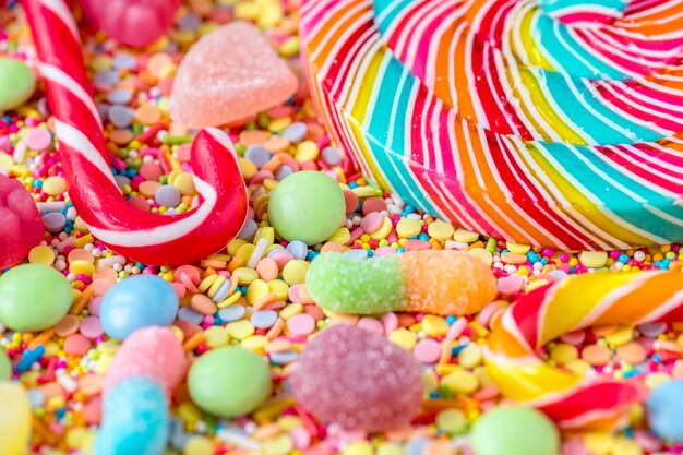 Закройте candycane и леденец на фоне красочных конфет