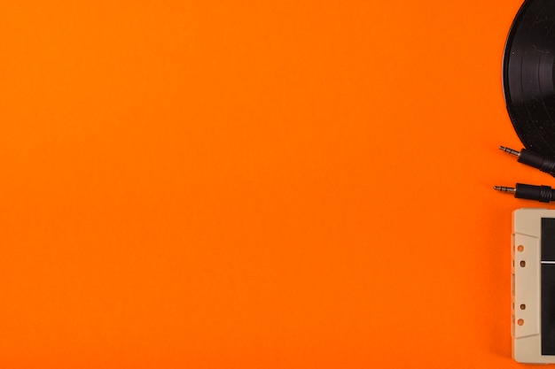 Close-up of cassette tape and vinyl record on an orange background