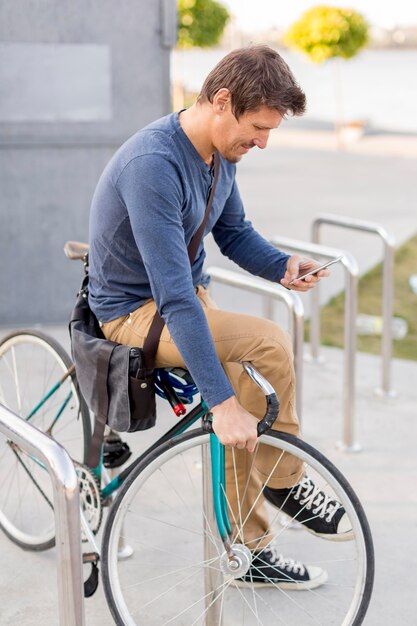 彼の自転車を固定するクローズアップのカジュアルな男性