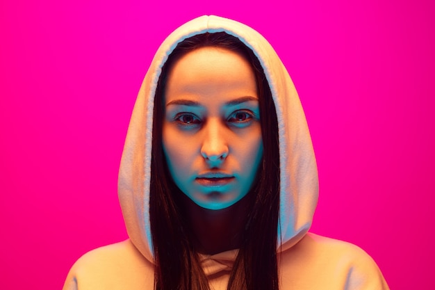 Close up caucasian woman's portrait isolated on pink studio background in mixed neon light. Beautiful female model. Concept of human emotions, facial expression, sales, ad, fashion. Beauty.