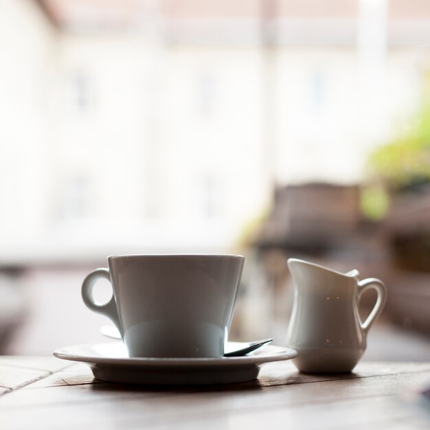 Close-up of ceramic coffee cup and milk pitcher