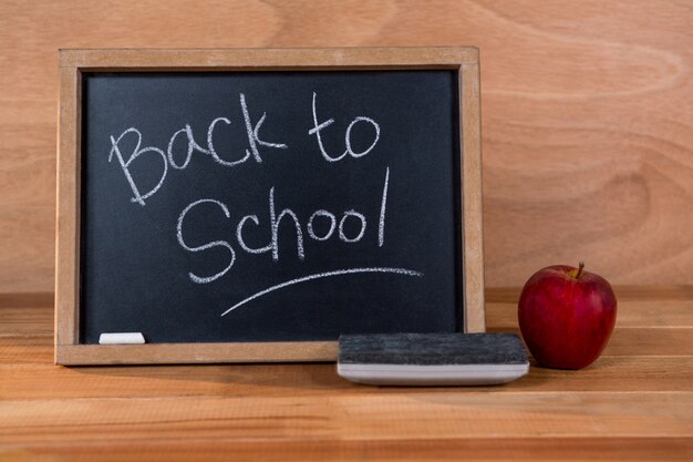 Close-up of chalkboard with blackboard duster and apple