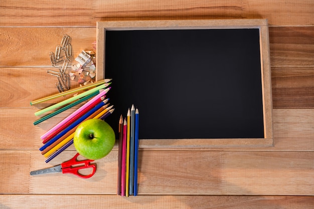 Close-up of chalkboard with colored pencil and apple