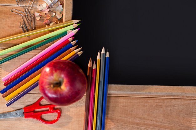 Close-up of chalkboard with colored pencil and apple