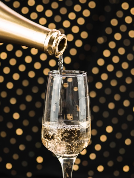 Free photo close-up of champagne bottle pouring in glass