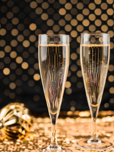 Close-up of champagne glasses on golden textile