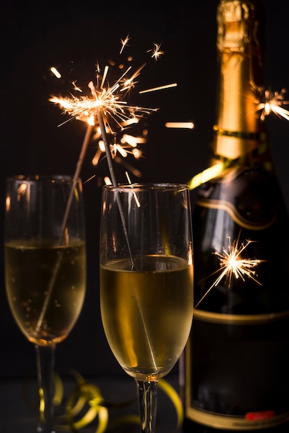 Close-up of champagne and sparkler over black backdrop