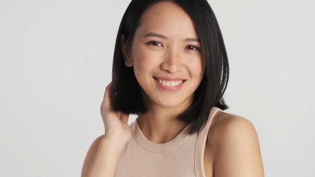 Close up charming Asian girl looking happy at camera preening over white background Beautiful female posing