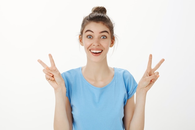 Free photo close-up of cheerful beautiful young woman smiling and showing peace gestures