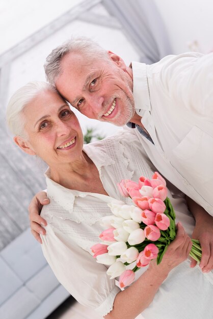 美しいチューリップの花の花束と陽気な老夫婦のクローズアップ
