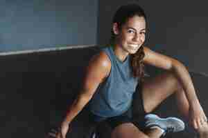 Free photo close-up cheerful fit good-looking young brazilian woman sitting on gym floor