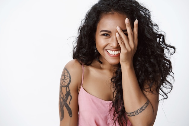 Free photo close-up cheerful happy girlfriend with tattoos and toothy white smile, laughing, cover half of face, gazing camera upbeat, enjoy party with friendly company, having fun