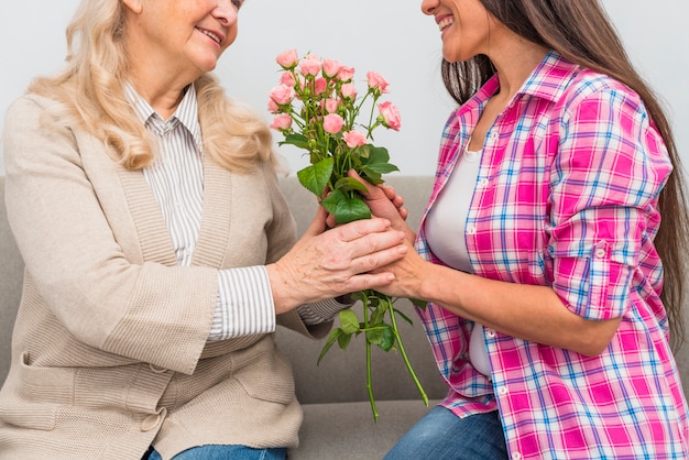 Foto gratuita close-up di allegro giovane adulto e senior woman holding rose