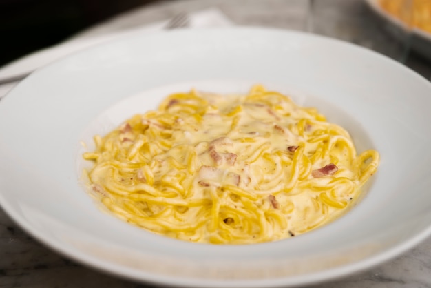 Close-up of cheesy spaghetti pasta in white ceramic plate