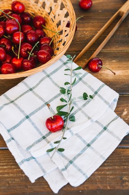 Free photo close-up of chequered pattern napkin and red cherries in wicker bowl