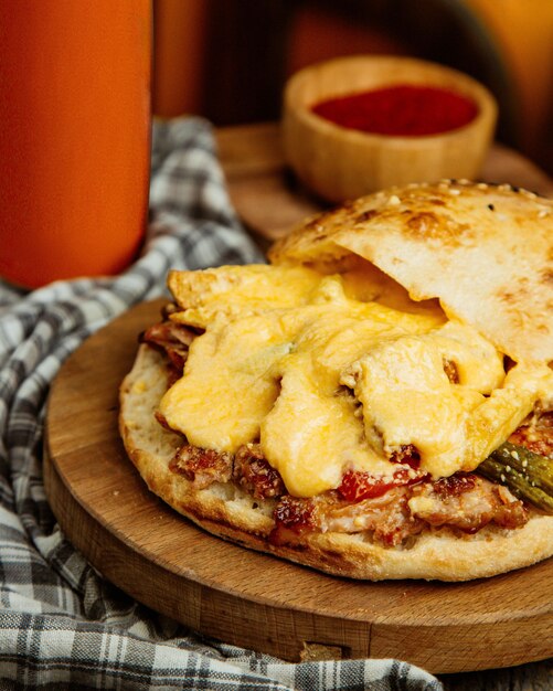 Close up of chicken doner with melted cheese tomato french fries and pickled cucumber