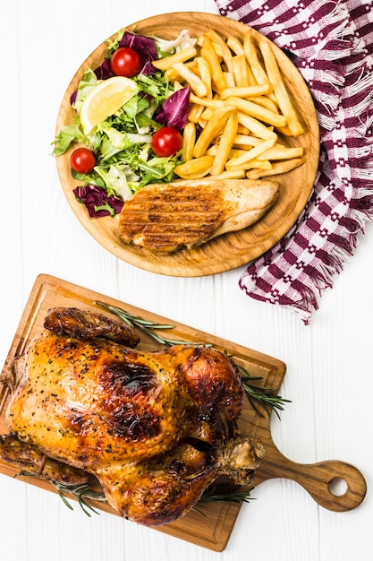 Close-up chicken near French fries and salad