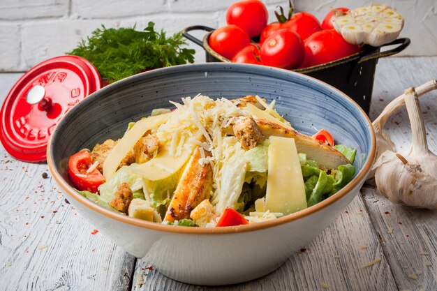 Close up chicken salad in bowl with garlic and fresh tomatoes