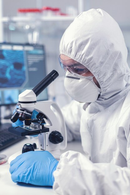 Close up of chief researcher scientist adjusts microscope in time of coronavirus experiment