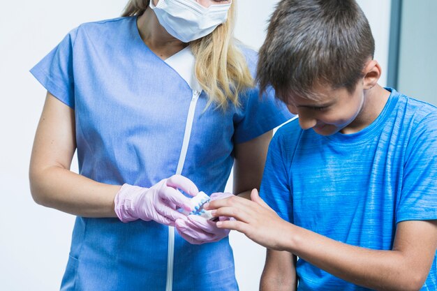 Close-up of a child patient looking at teeth plaster mold hold by dentist