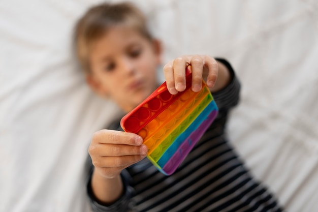 Foto gratuita primo piano sul bambino che gioca con il giocattolo pop it