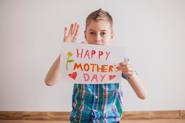 Close-up of child with mother's day poster