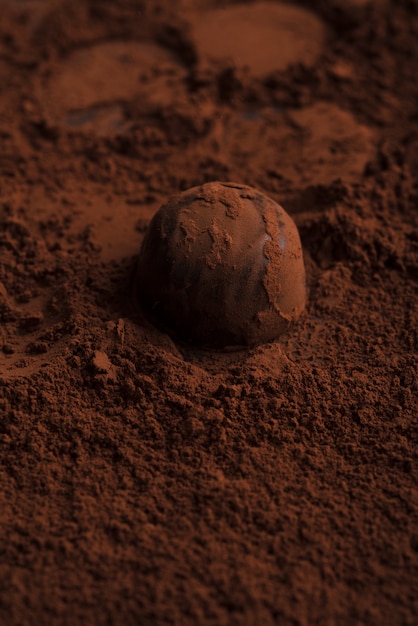 Крупный план шоколадных конфет над шоколадной пудрой
