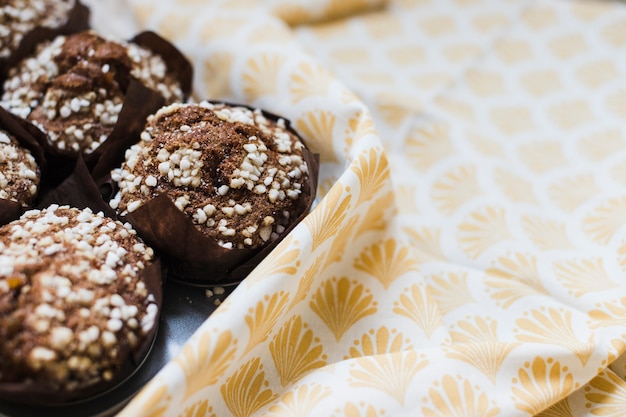 Close-up of chocolate muffins in brown paper over the tablecloth