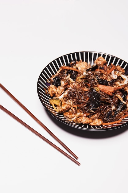 クローズアップの箸と白いアジア料理