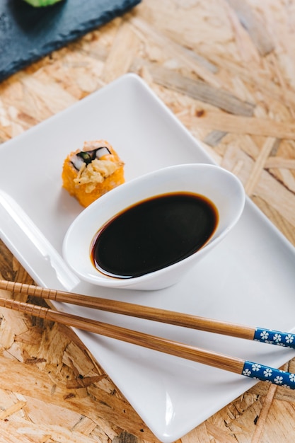 Close-up chopsticks and soy sauce near roll