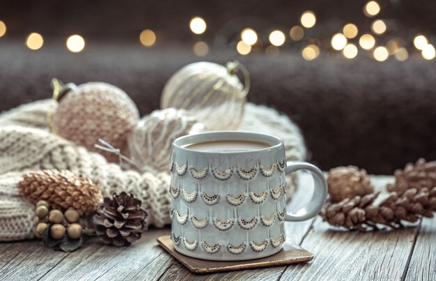 Close up of Christmas cup and festive decor on blurred dark background with bokeh.