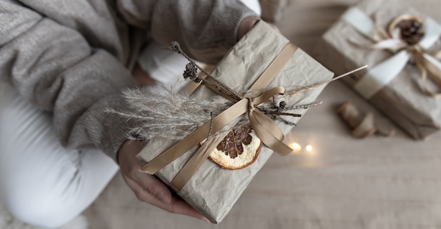 Close-up of a Christmas present, decorated with dried flowers and a dry orange, wrapped in craft paper.