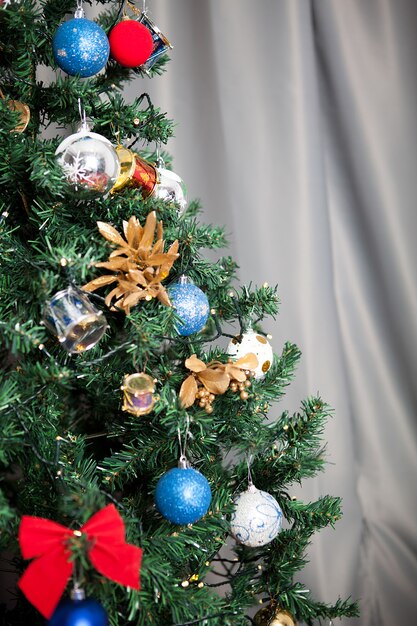 Закройте на елке с гирляндами и украшениями в доме. Декоративно-праздничное зеленое дерево