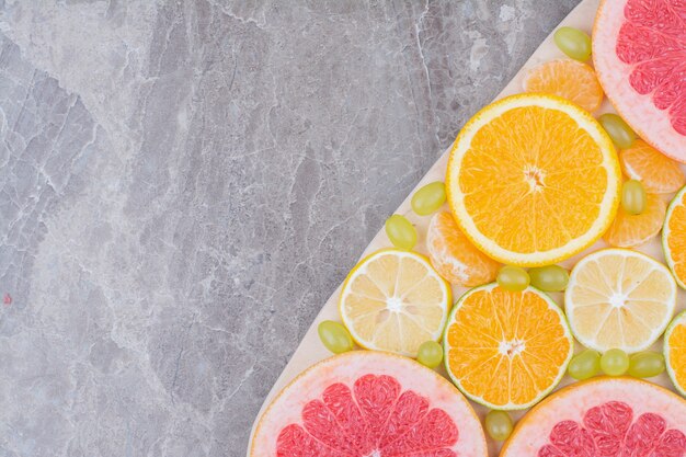 Close up citrus fruits slices and grapes on wooden board. 