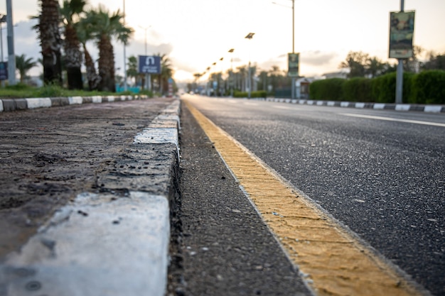 Close up city asphalt road with palm trees along the road at sunset