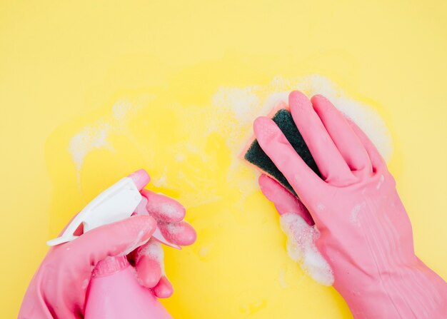 Close-up of a cleaner cleaning the yellow backdrop with sponge and spray bottle