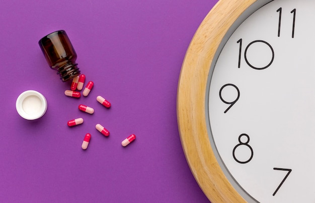 Free photo close-up clock with pills on desk