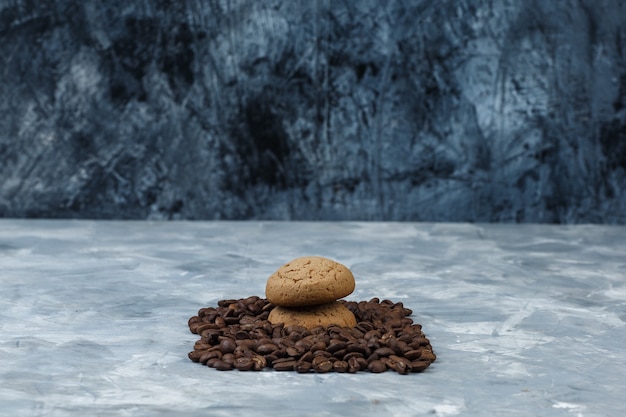 濃紺と水色の大理石の背景にクッキーとクローズアップコーヒー豆。水平