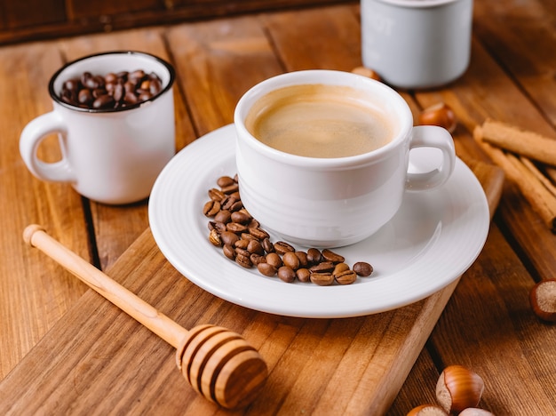 Close up of coffee cup decorated with coffee beans placed on wooden serving board