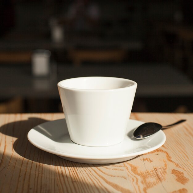Крупный план кофейной чашки и ложки на столе