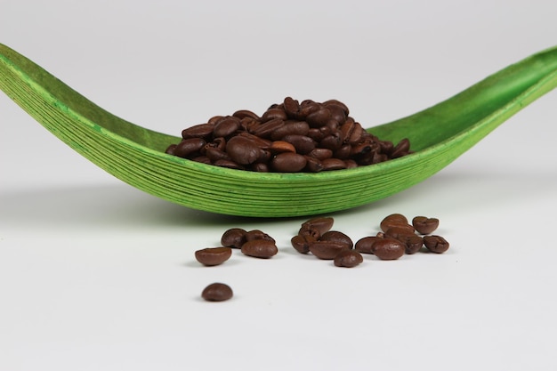 Free photo close up of coffee grains of nice smell on a green deep leaf isolated on a white background