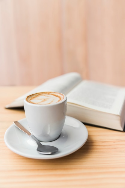Крупный план кофе латте и открытой книги на деревянный стол