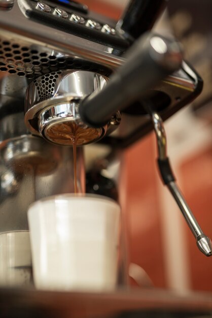 Close-up coffee pouring into glass with milk